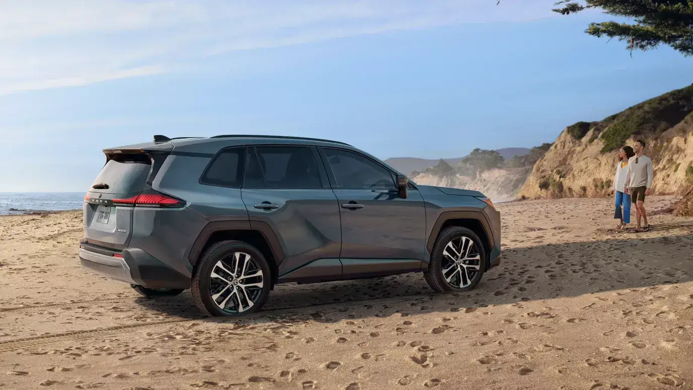 Gray 2026 Toyota RAV4 side view parked on a sandy beach in daylight