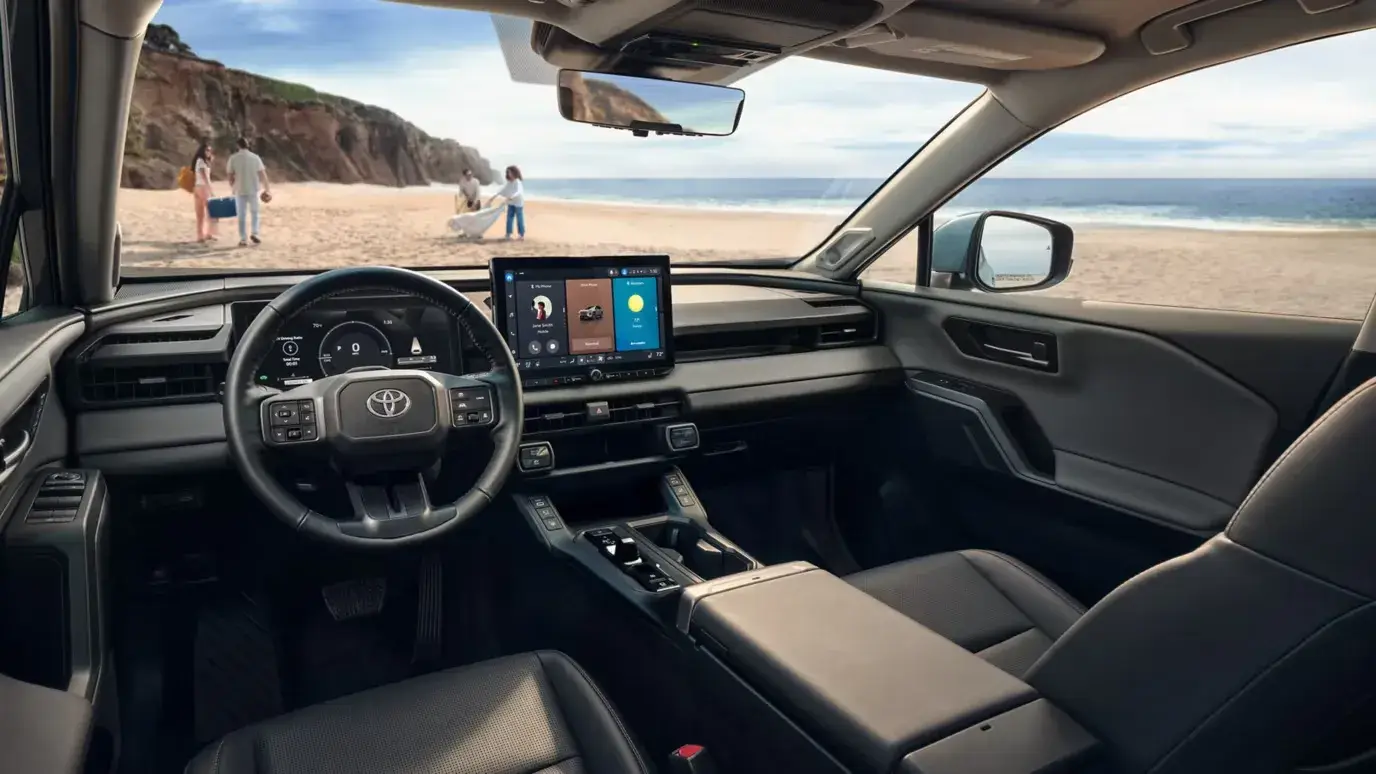 2026 Toyota RAV4 steering wheel, digital cluster and center touchscreen with a beach view