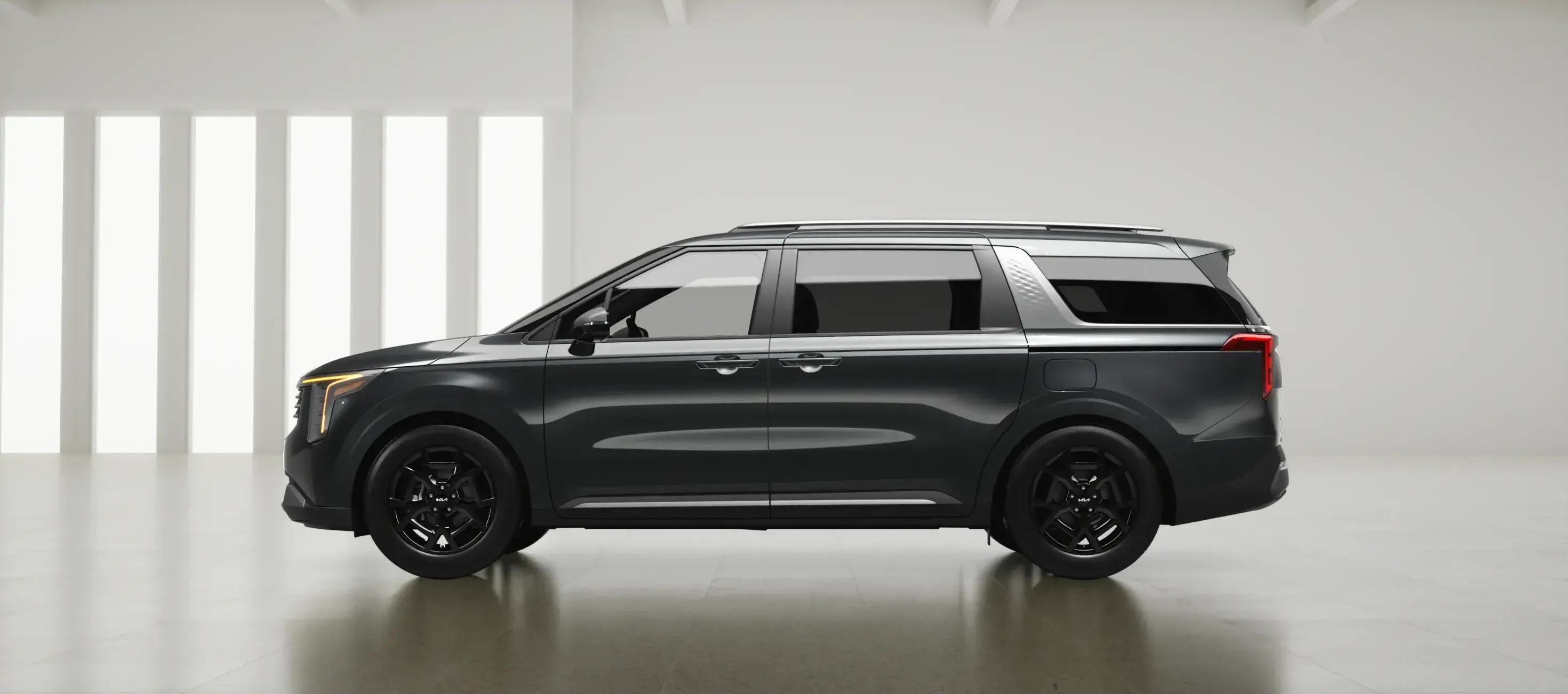 Gray 2027 Kia Carnival in a white studio, side profile facing left