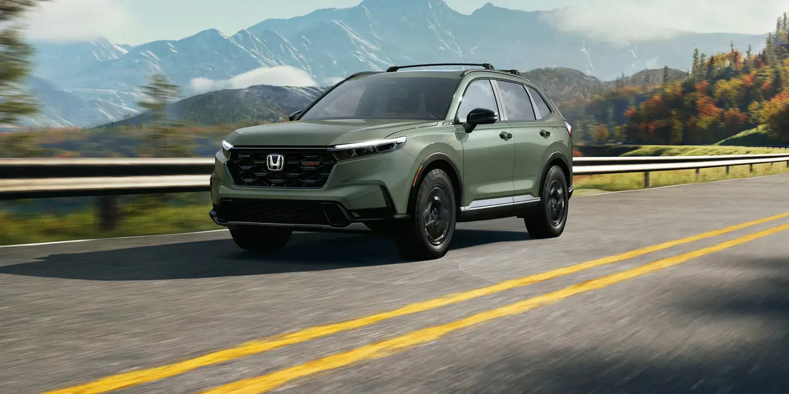 Green 2027 Honda CR-V driving on a mountain highway, front three-quarter view