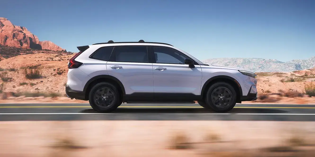 2027 Honda CR-V in Platinum White Pearl, side view driving on a desert road