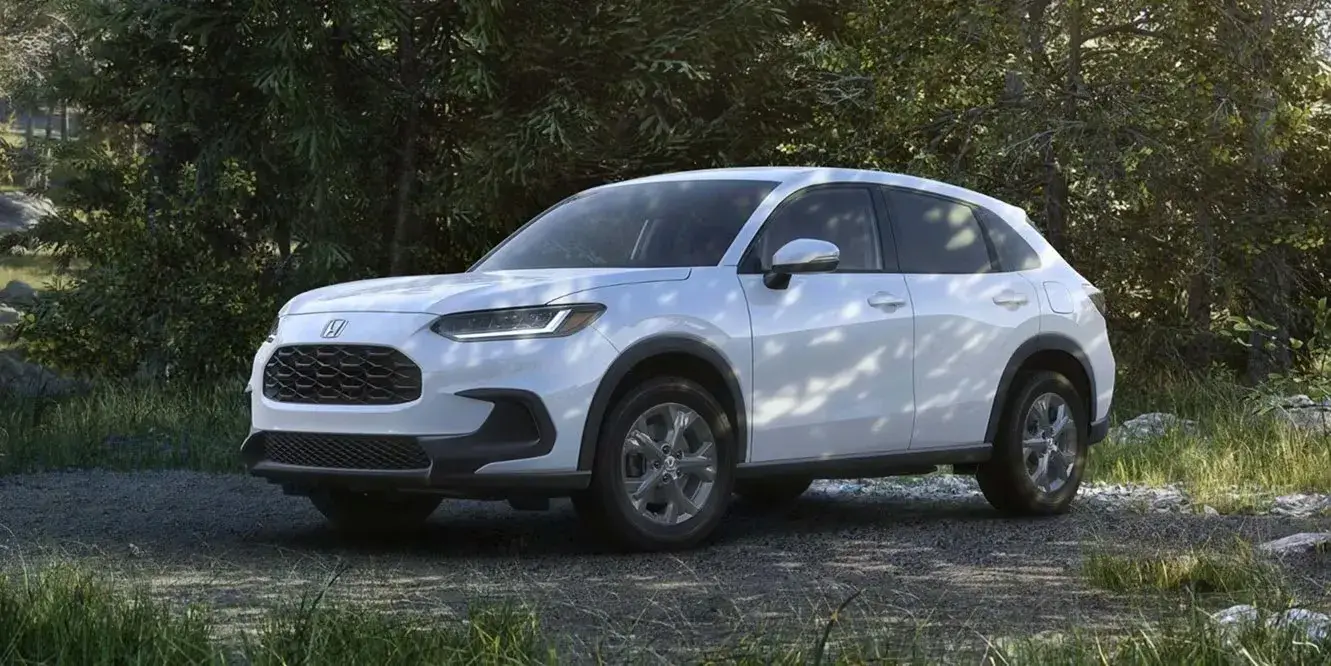 2027 Honda HR-V LX in Platinum White Pearl parked on a forest trail, front three-quarter view