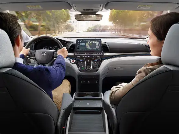 2027 Honda Odyssey Elite dashboard and front seats with a couple, seen from the back seat