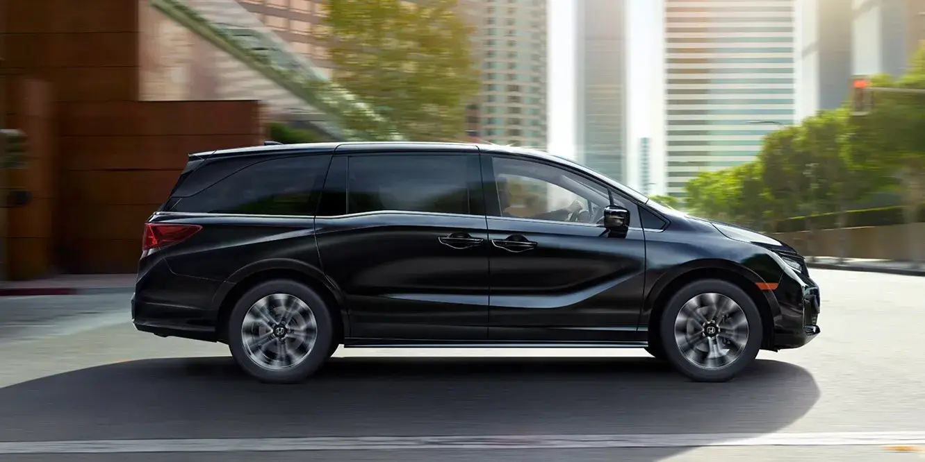 2027 Honda Odyssey Elite in Crystal Black Pearl on a city street, side view
