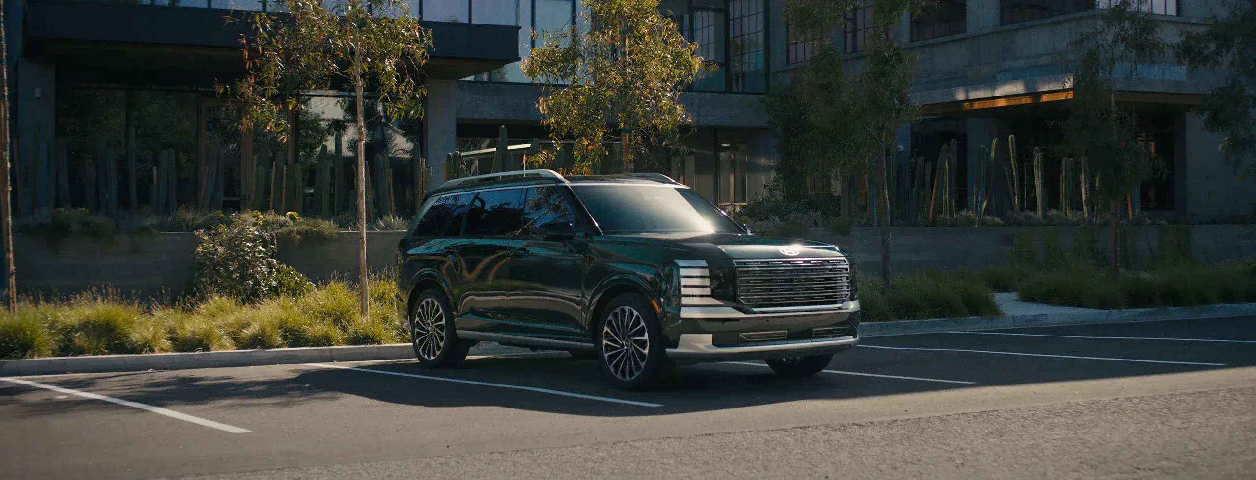 Dark green 2027 Hyundai Palisade on a city street, front three-quarter view facing right