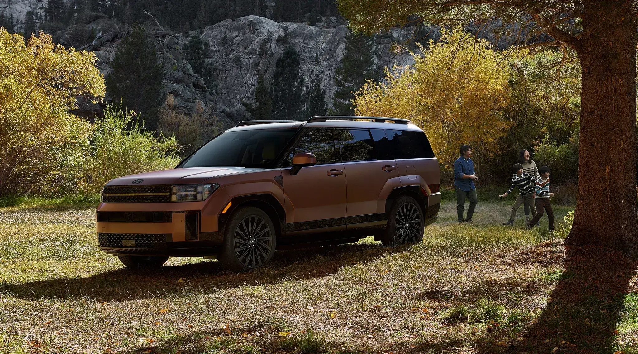 Bronze Hyundai Santa Fe parked in an autumn forest, front three-quarter view