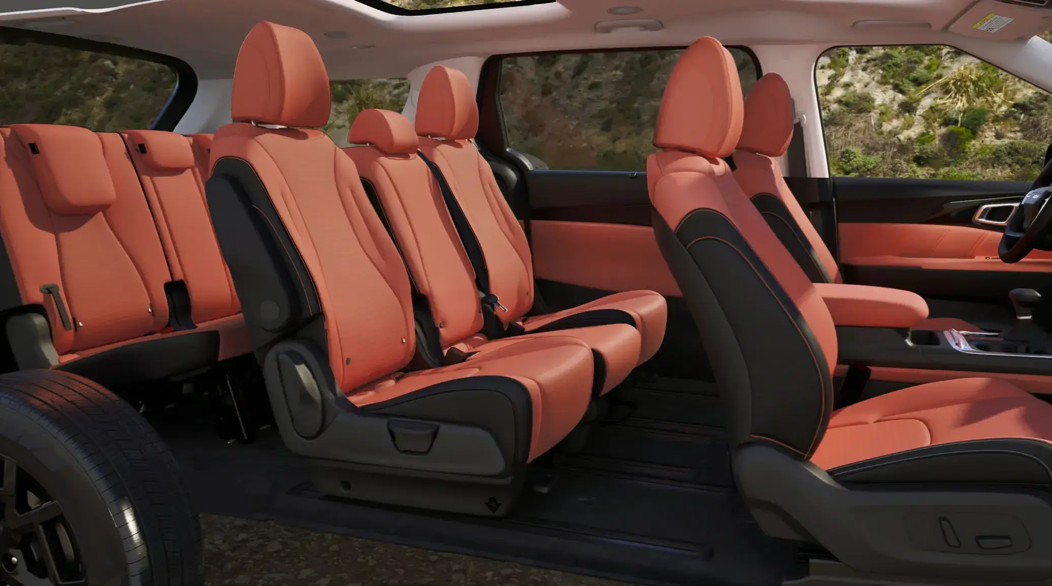 2027 Kia Carnival orange and black seats across three rows seen from the side