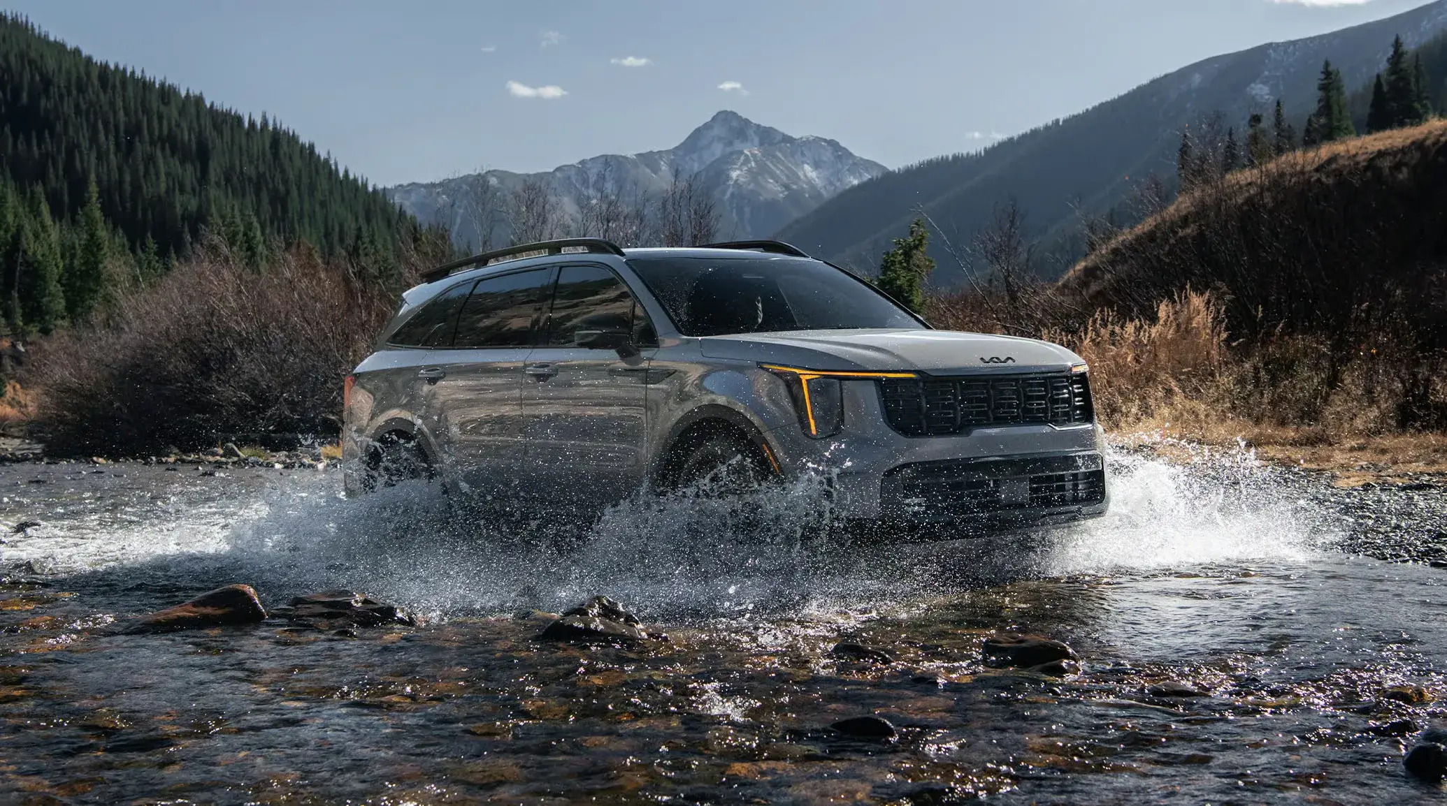 Silver Kia Sorento X-Line splashing through a mountain stream, front three-quarter view