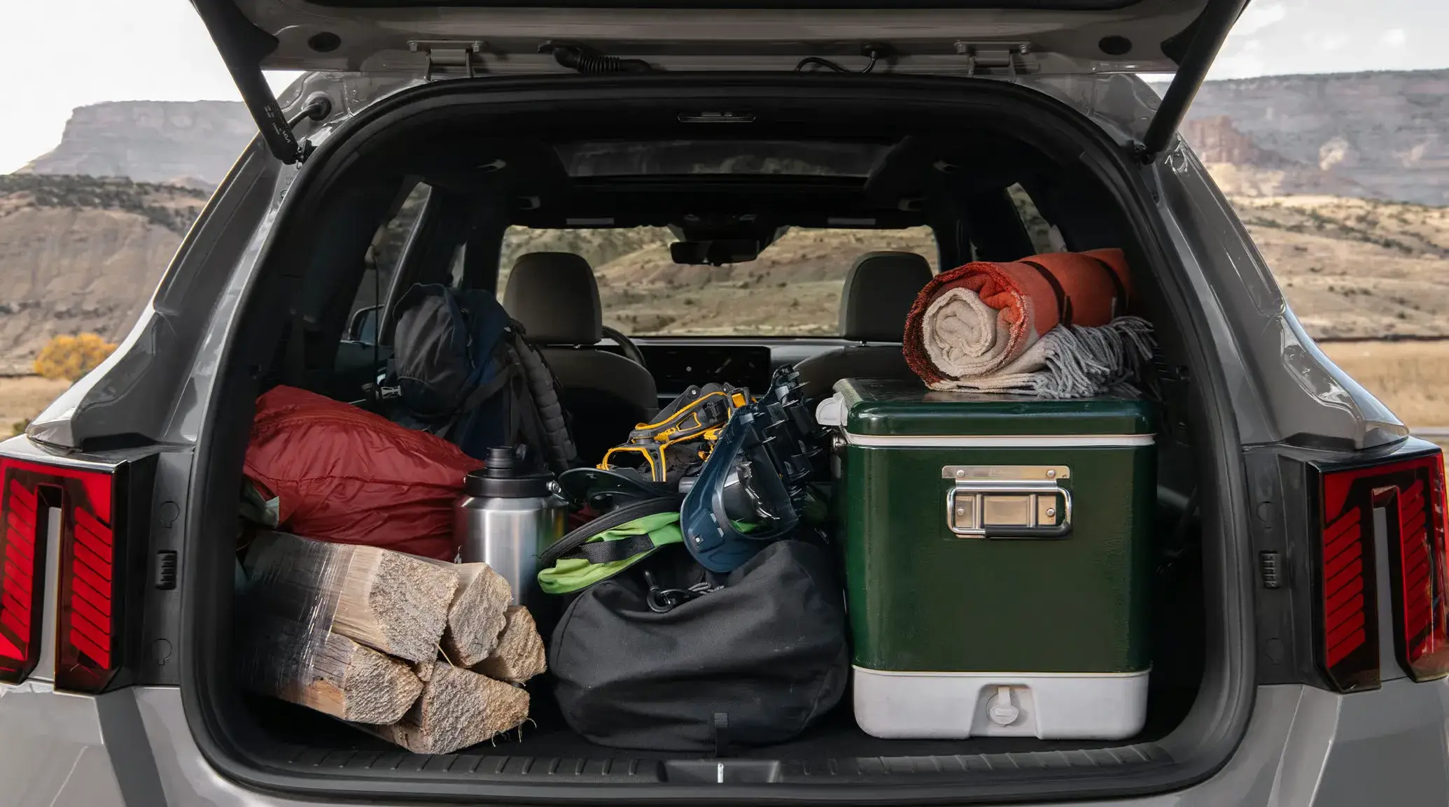 Kia Sorento cargo area packed with a cooler, firewood and camping gear