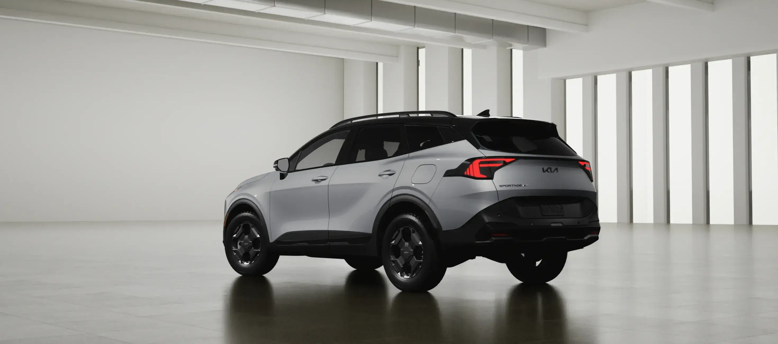 Silver 2027 Kia Sportage in a white studio, rear three-quarter view
