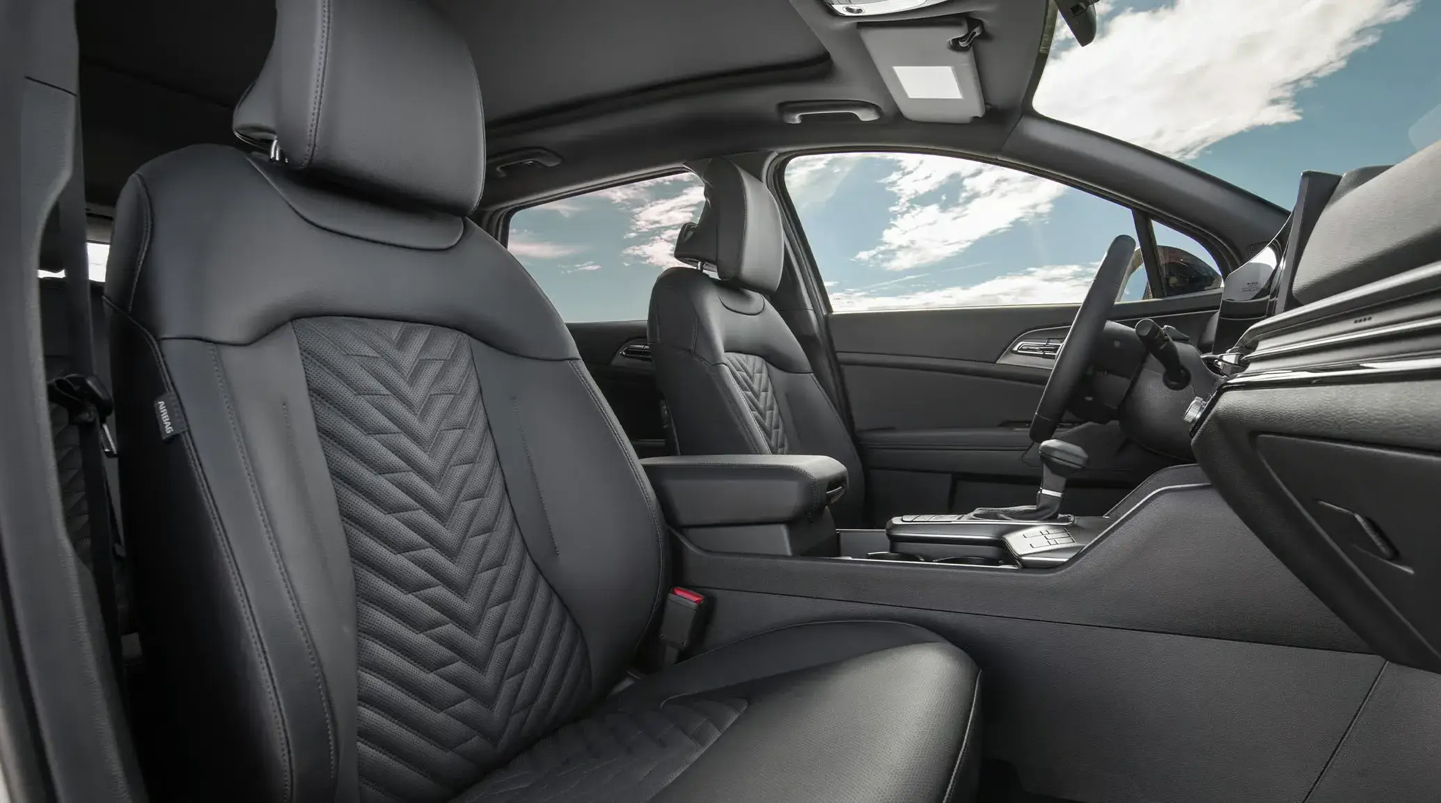 2027 Kia Sportage black quilted front seats seen through the open passenger door