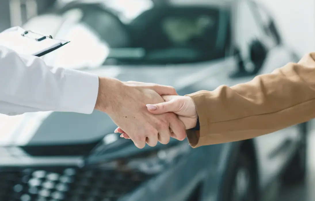 Customer shaking hands with a Plaza Auto Mall team member near a vehicle