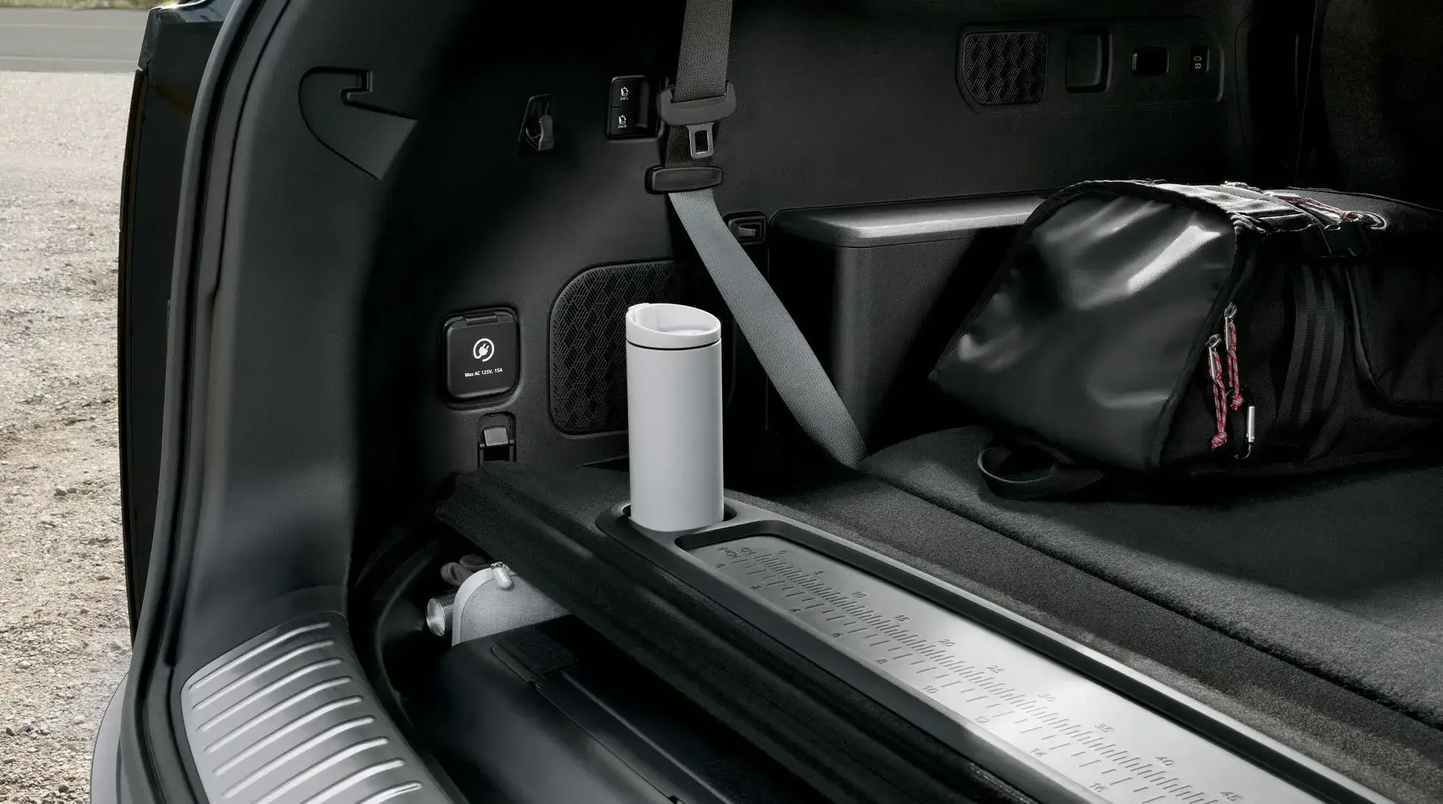 Cargo bay of the 2027 Kia Telluride Hybrid showing the folding table with cupholders and the 120V power outlet
