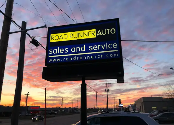 Road Runner Auto Sales and Service sign at sunset in Cedar Rapids, IA