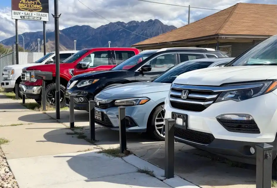 Saint Motors used car lot on State Street in Midvale, Utah, with trucks, SUVs and sedans below the Wasatch Mountains