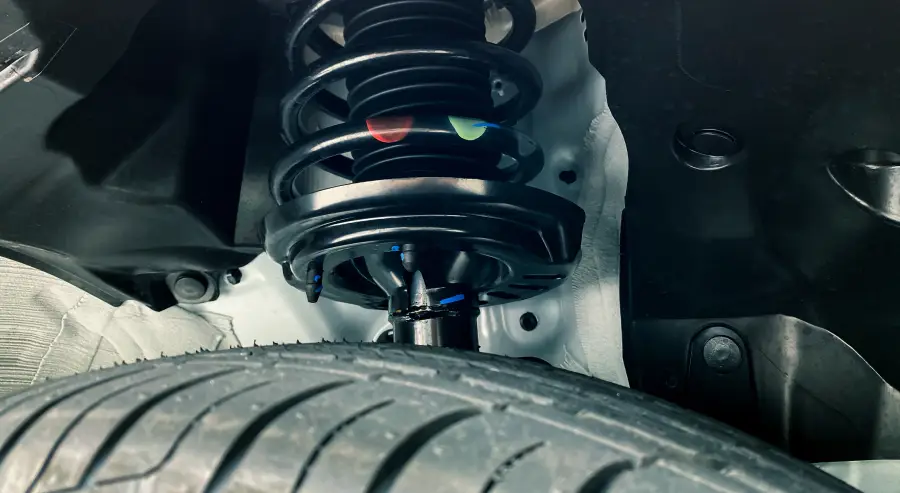 Close-up of a coil spring strut assembly mounted in a vehicle’s wheel well above the tire