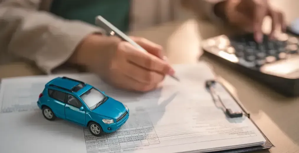 Auto financing paperwork with a model car and calculator.