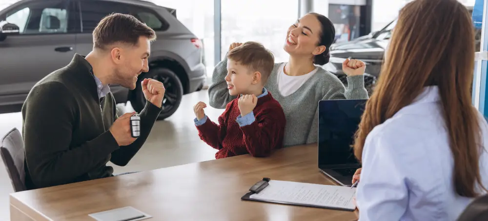 Family celebrating a vehicle purchase with a dealership representative