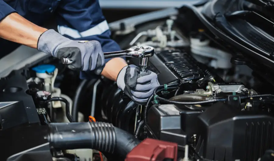 Service technician using a ratchet wrench on a car engine