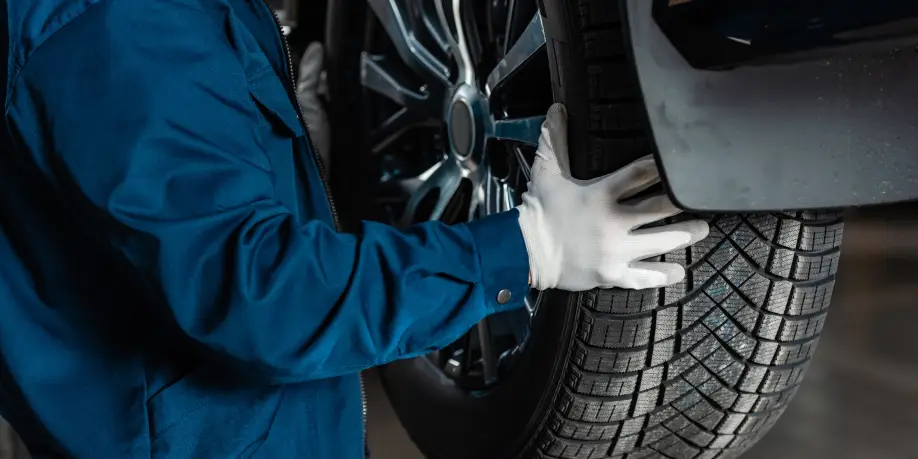 Technician in work gloves removing a tire from a vehicle