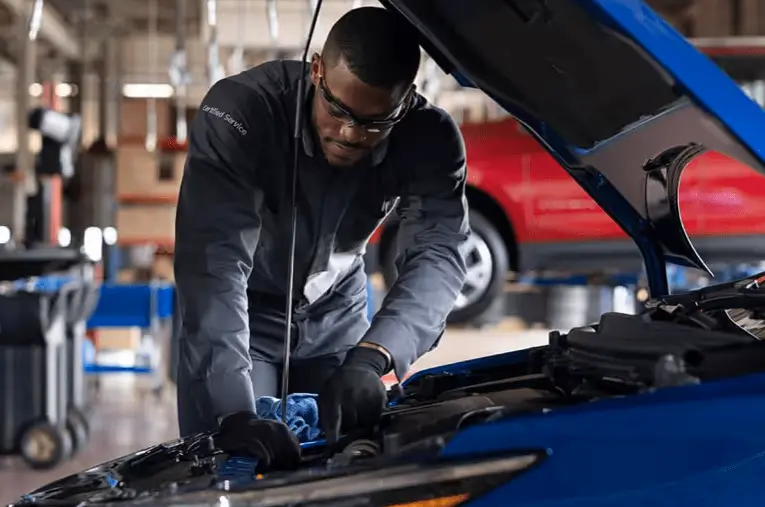 Certified-technician-examines-under-car-hood-mobile
