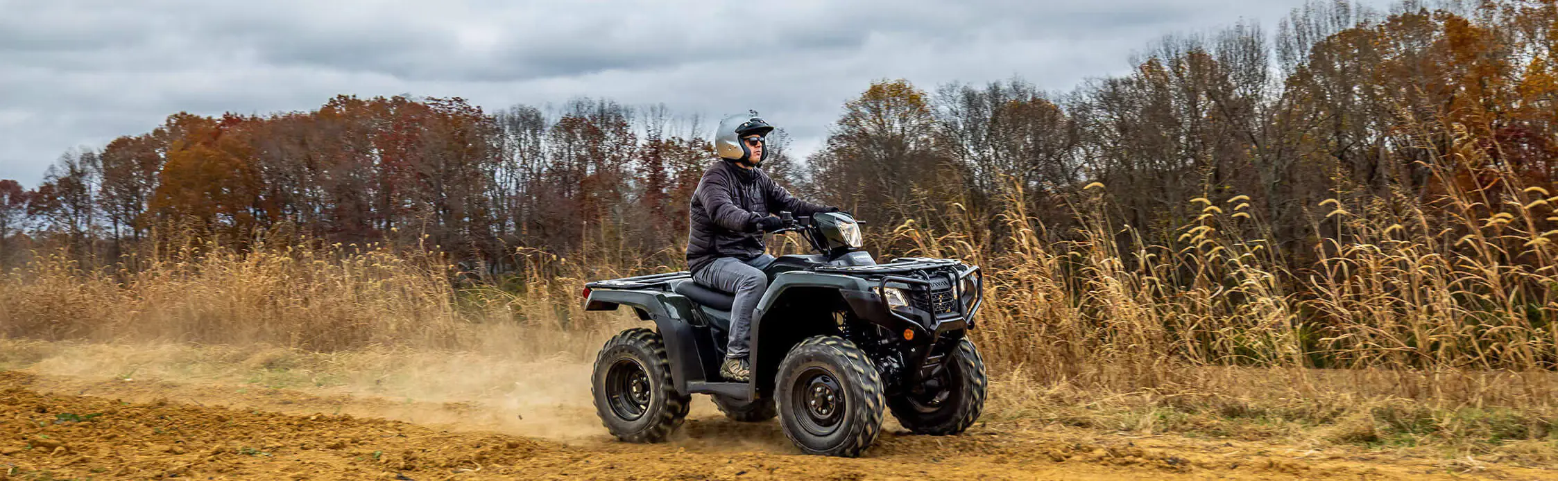 person riding a honda atv on a trail in a field