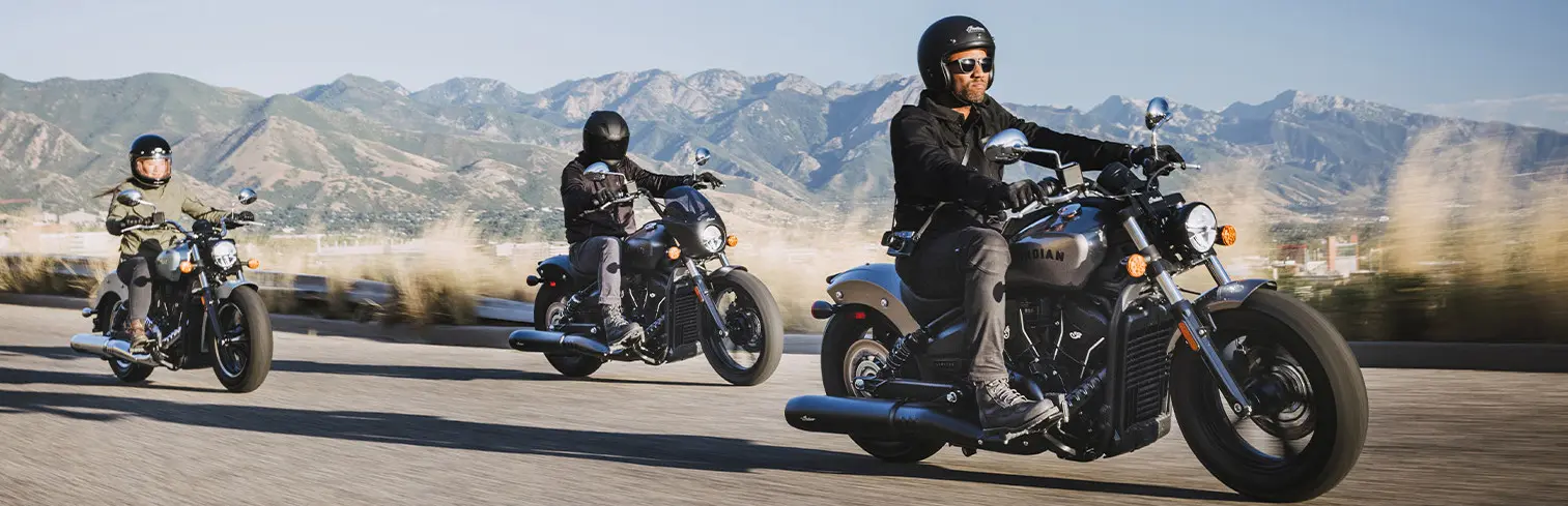three people riding indian motorcycles in the mountains