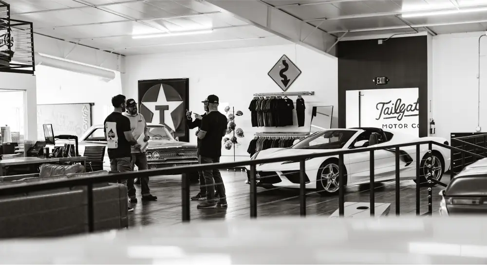 Interior de Tailgate Motor Co. con clientes y vehículos en exhibición