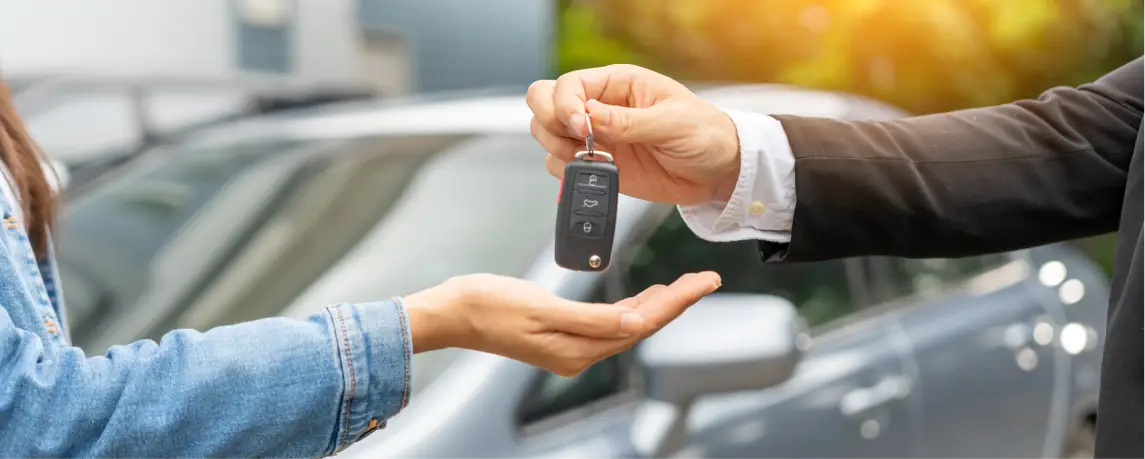 Car keys being handed to customer in front of vehicle.