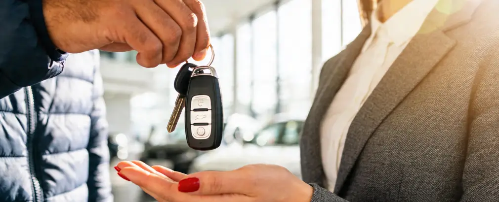 Customer receiving vehicle keys at a used car dealership in Mesa, AZ