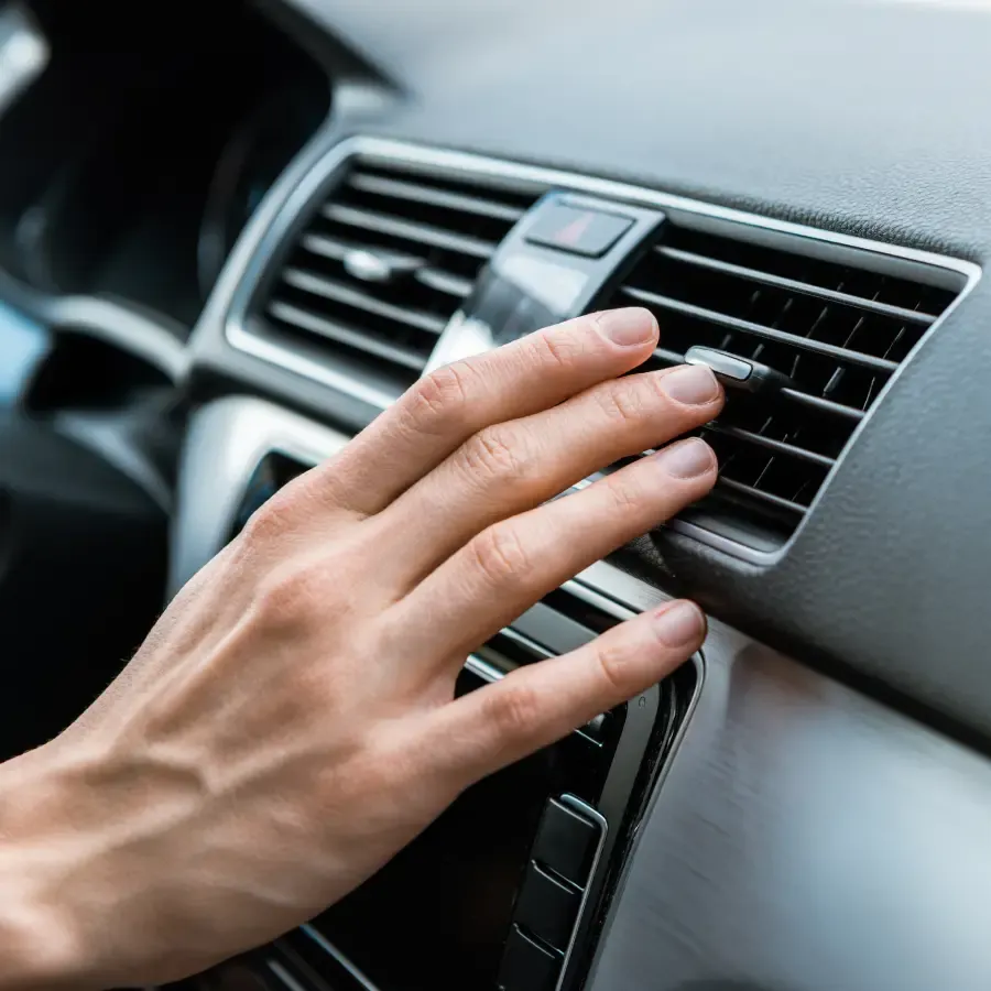 Driver adjusting the vehicle air conditioning system inside a car