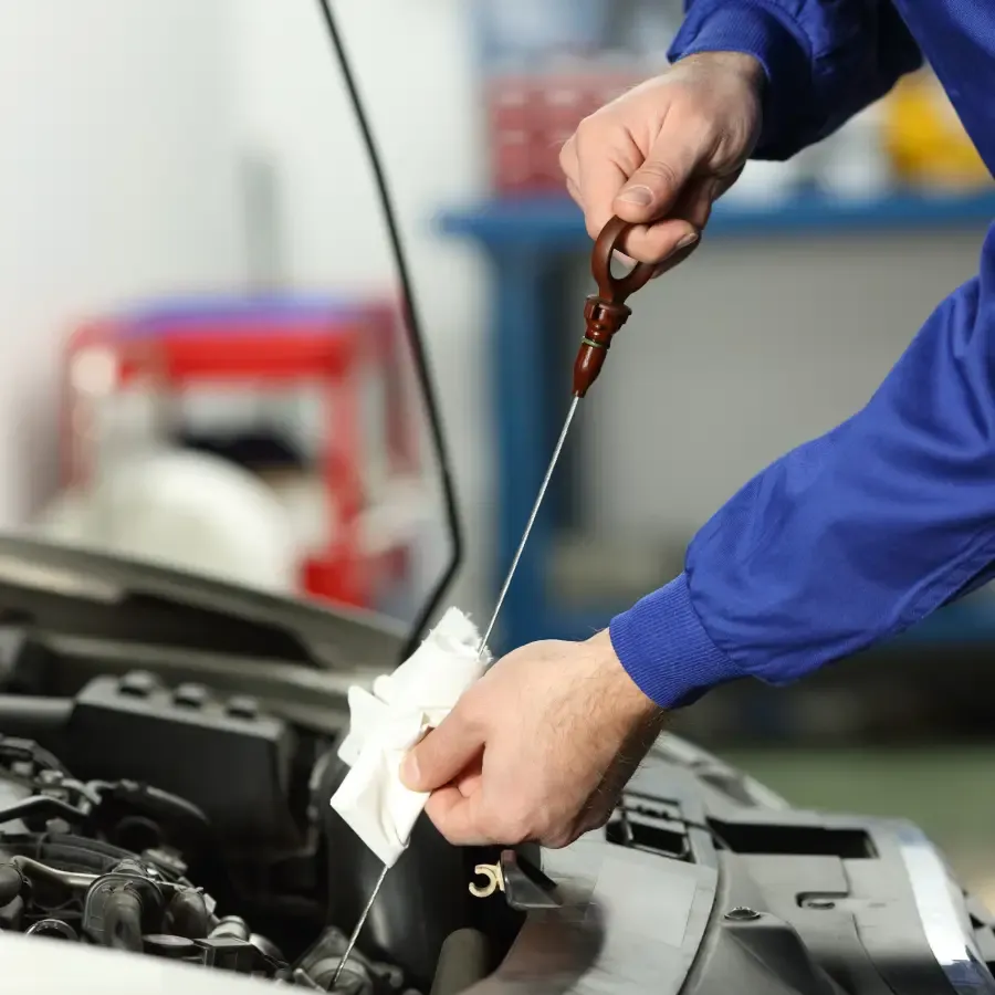Technician checking engine oil during preventive vehicle maintenance at Ultimate Powersports.