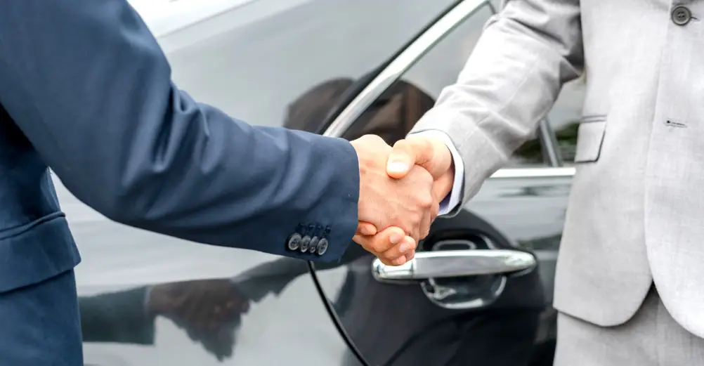 Customer shaking hands with a dealership representative after arranging powersports shipping