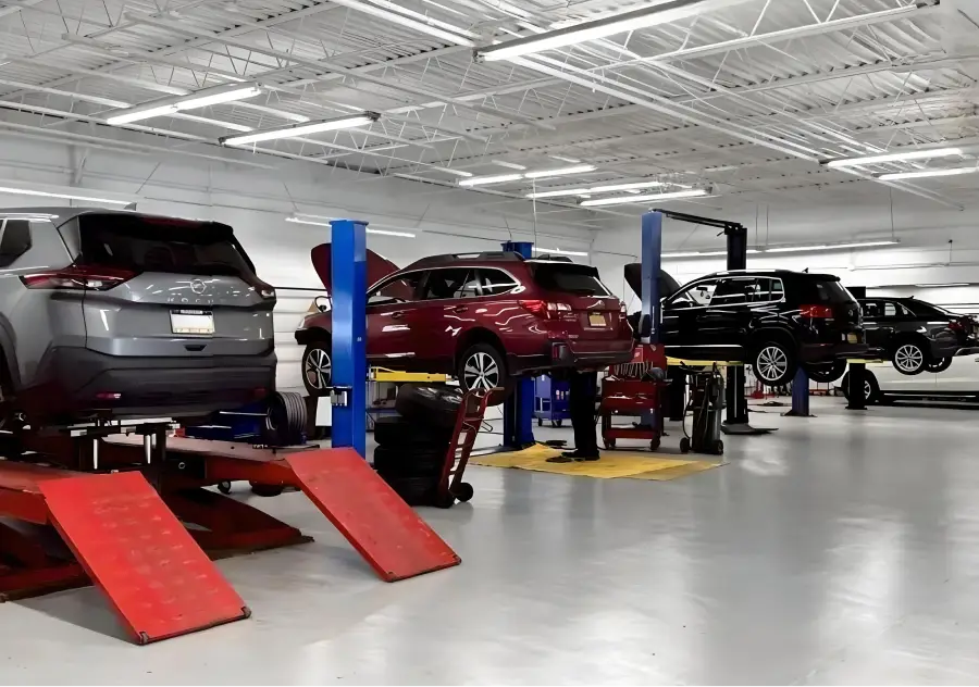 Vehicles in auto service shop with open hoods on lifts undergoing maintenance