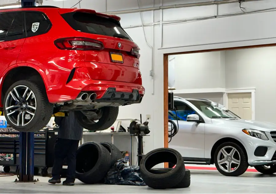 Red SUV lifted in auto service shop with mechanic working underneath