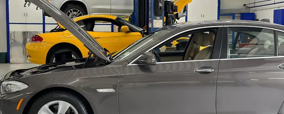 Sedan with hood open in auto service shop with other vehicles on lifts
