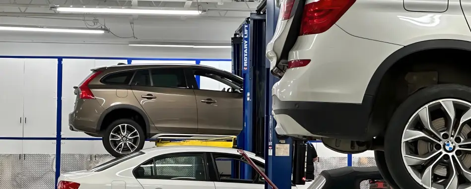 Several vehicles on lifts inside a professional auto service center undergoing inspection and maintenance