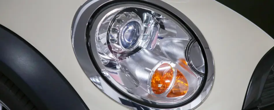 Close-up of a car headlight assembly showing projector lens and turn signal detail