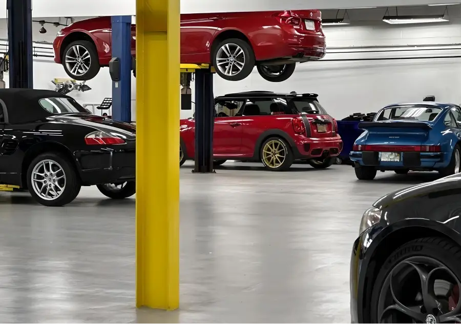 Multiple vehicles inside an auto service shop with cars on lifts undergoing maintenance and inspection
