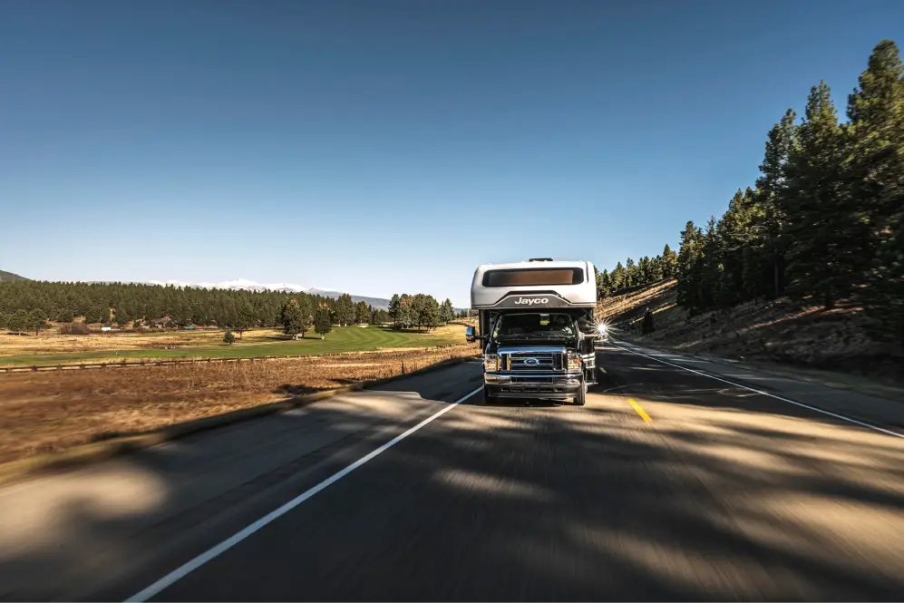 Motorhome RV driving on a highway through a rural landscape.