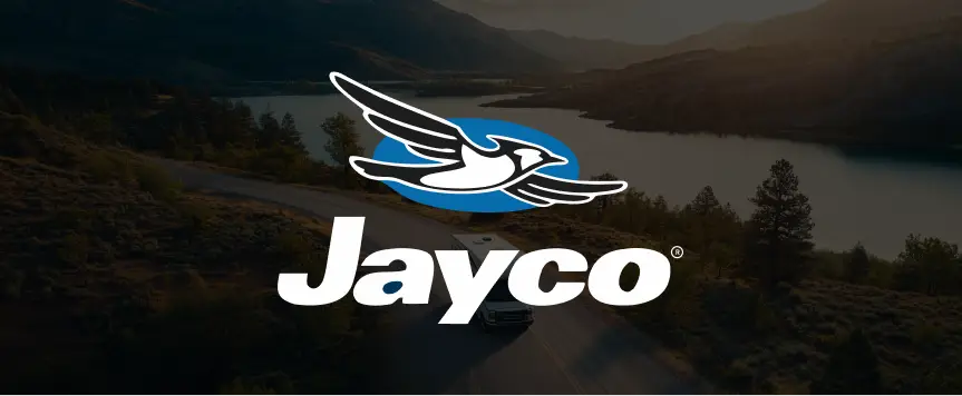 Jayco logo with an RV driving along a winding road beside a mountain lake at sunset