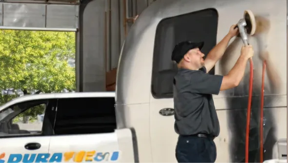 Technician cleaning the exterior of an RV trailer.