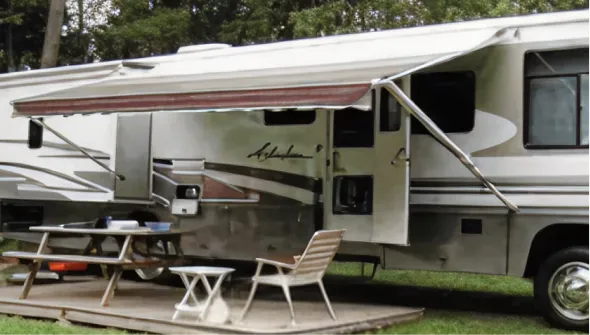 Motorhome parked at a campsite with outdoor chairs and awning extended.