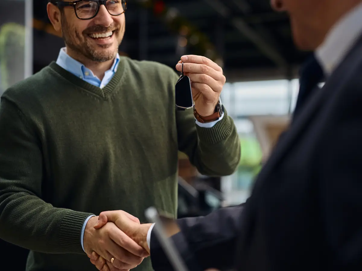 Customer receiving car keys during a vehicle purchase at Volume Cars.