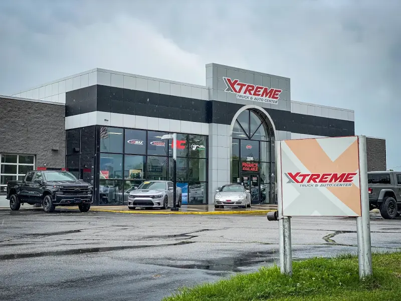 Xtreme Truck & Auto Center storefront with orange truck and red sports car outside