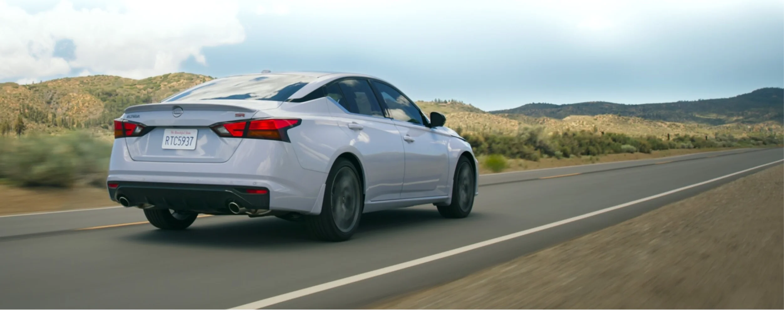 Nissan Altima rear view driving on highway through scenic landscape